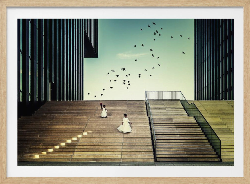 A framed piece of art depicting two young girls in white dresses climbing a vast, modern concrete staircase flanked by two towering, dark buildings. A large flock of birds flies through the teal sky above them, adding a sense of movement to the structured, architectural scene. Poster