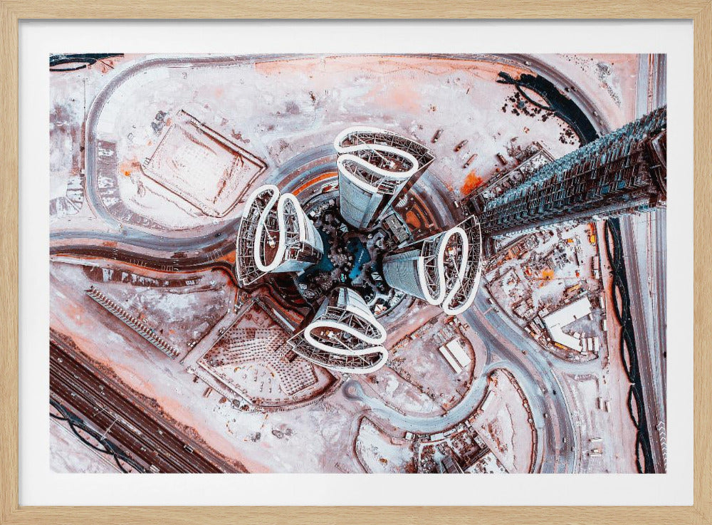A dizzying top-down aerial photograph of five futuristic, petal-shaped skyscrapers surrounding a central turquoise pool. The surrounding urban landscape is a mix of dusty pink construction sites and curving roads, creating a surreal and abstract cityscape. Wall Art