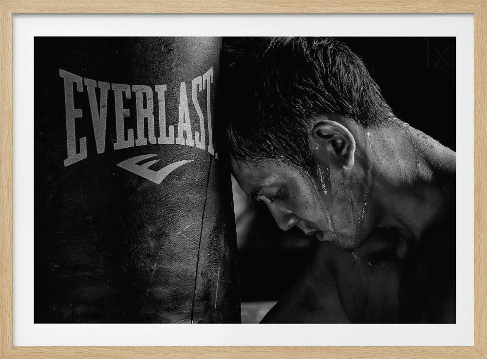 A dramatic black and white close-up photograph of an exhausted boxer resting his head against a heavy Everlast punching bag, with sweat dripping down his face and neck. Poster