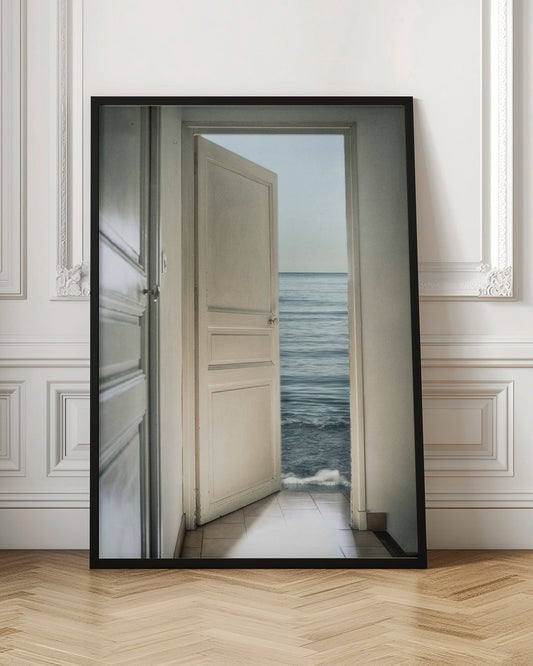 A surreal photograph showing a white interior door swung open, revealing not a landscape but the vast blue ocean, with waves gently washing over the tiled floor of the room. Decor