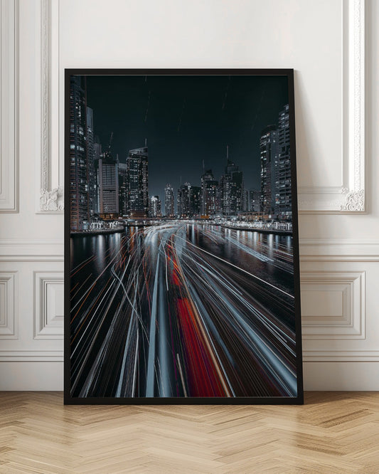 A dynamic long-exposure photograph of a bustling city marina at night. In the foreground, vibrant streaks of red and white light from moving boats cut across the dark water. In the background, a modern skyline of illuminated skyscrapers stands against a dark night sky, creating a futuristic and energetic scene. Poster