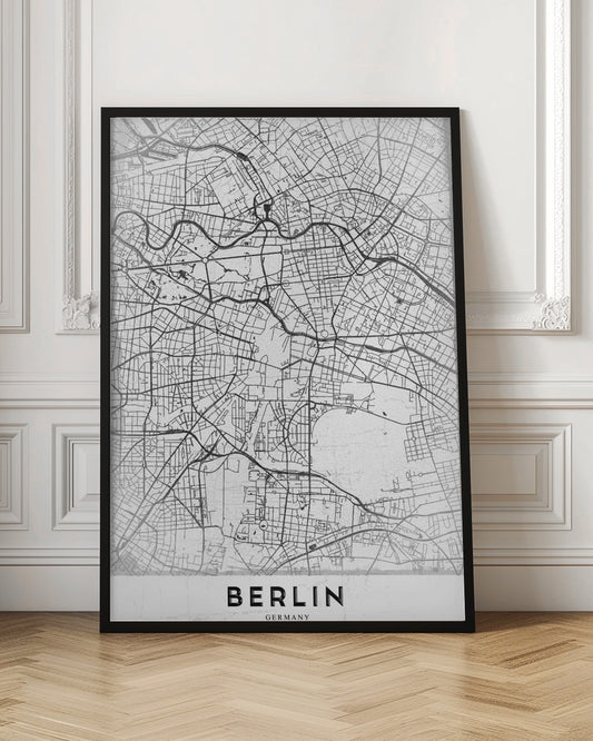 A minimalist black and white poster of a street map of Berlin, Germany. The map's intricate network of roads and waterways is depicted with black lines on a white, slightly textured background. The artwork is enclosed in a simple black frame, with the word 'BERLIN' printed in bold, black capital letters at the bottom center. Wall Art
