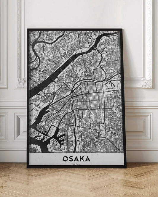 A framed black and white map of Osaka, Japan. The map details the city's streets, blocks, and rivers in a modern, graphic style. At the bottom, a white border contains the word 'OSAKA' in a bold, black, sans-serif font. Print