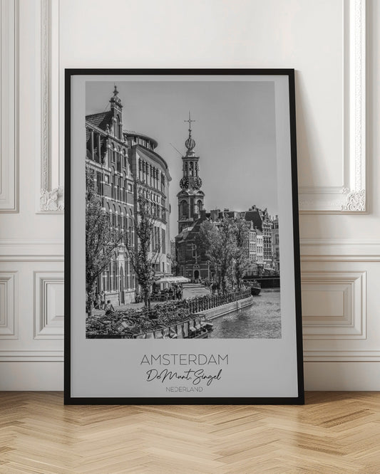 A black and white travel poster of Amsterdam, Netherlands. The photo shows the Munttoren clock tower and traditional Dutch buildings along the Singel canal. A floating barge filled with bicycles is in the foreground. The poster has a white border with the text 'AMSTERDAM', 'De Munt, Singel', and 'NEDERLAND' at the bottom. Artwork