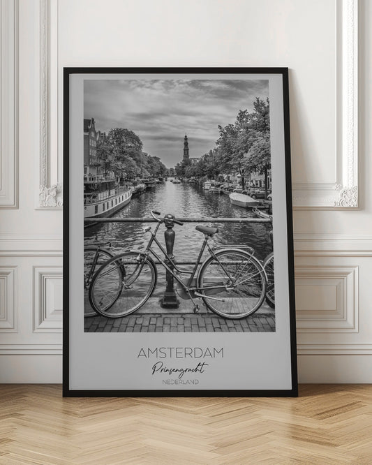A black and white poster of the Prinsengracht canal in Amsterdam. A bicycle is parked on a bridge in the foreground, overlooking the canal lined with houseboats, trees, and traditional Dutch buildings. The Westerkerk church tower is visible in the distance. The poster has a white border with the words 'AMSTERDAM', 'Prinsengracht', and 'NEDERLAND' at the bottom. Poster