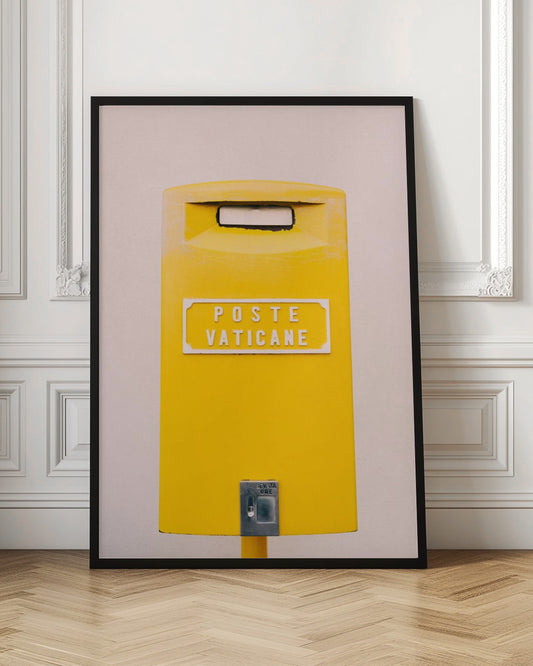A close-up, front-view photograph of a vibrant yellow Vatican City mailbox against a plain beige wall, enclosed in a thin black frame. The words 'POSTE VATICANE' are printed in white on the front. Artwork