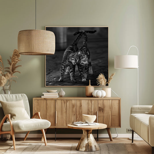 A black and white framed photograph capturing an affectionate moment between two tabby cats. They are rubbing their heads together with eyes closed, and their tails are intertwined above them, creating a heart-like shape. Decor