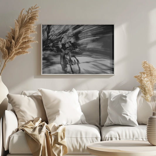 A dramatic black and white action shot of a professional cyclist racing. The cyclist is in focus, wearing a helmet and sunglasses, while the background is a streaky motion blur, creating a powerful sense of speed and movement. The image is enclosed in a silver frame. Wall Art