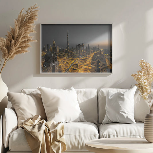 A framed, high-angle, long-exposure photograph of the Dubai skyline at dusk. The towering Burj Khalifa stands out against a grey sky, while the city's skyscrapers are illuminated. In the foreground, a complex network of highways glows with the yellow light trails of traffic, creating intricate patterns. Poster