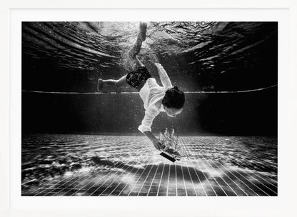 A surreal black and white underwater photograph of a child in a white shirt and shorts diving towards the bottom of a tiled pool to retrieve a miniature model of a sailing ship. Artwork