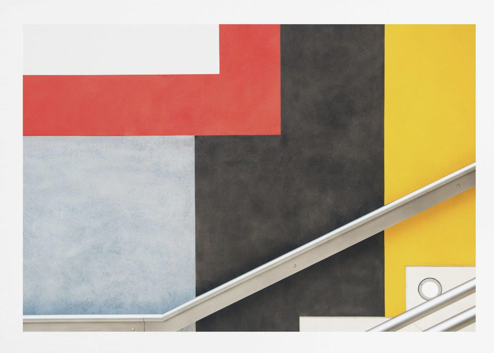 A framed abstract art piece featuring a composition of large, solid-colored geometric shapes in red, yellow, black, white, and light gray. A silver handrail cuts diagonally across the lower portion of the image, adding a sharp line and a sense of architectural space. Artwork