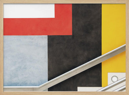 A framed abstract art piece featuring a composition of large, solid-colored geometric shapes in red, yellow, black, white, and light gray. A silver handrail cuts diagonally across the lower portion of the image, adding a sharp line and a sense of architectural space. Artwork