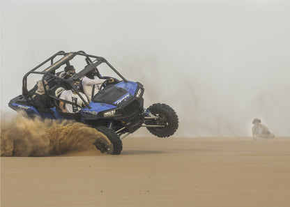 A framed action shot of a blue dune buggy with several passengers making a sharp turn in the desert, kicking up a large cloud of sand and lifting its front wheel off the ground. Wall Art