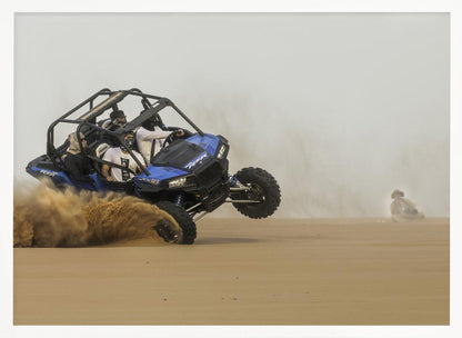 A framed action shot of a blue dune buggy with several passengers making a sharp turn in the desert, kicking up a large cloud of sand and lifting its front wheel off the ground. Wall Art