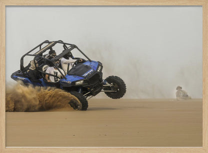 A framed action shot of a blue dune buggy with several passengers making a sharp turn in the desert, kicking up a large cloud of sand and lifting its front wheel off the ground. Wall Art