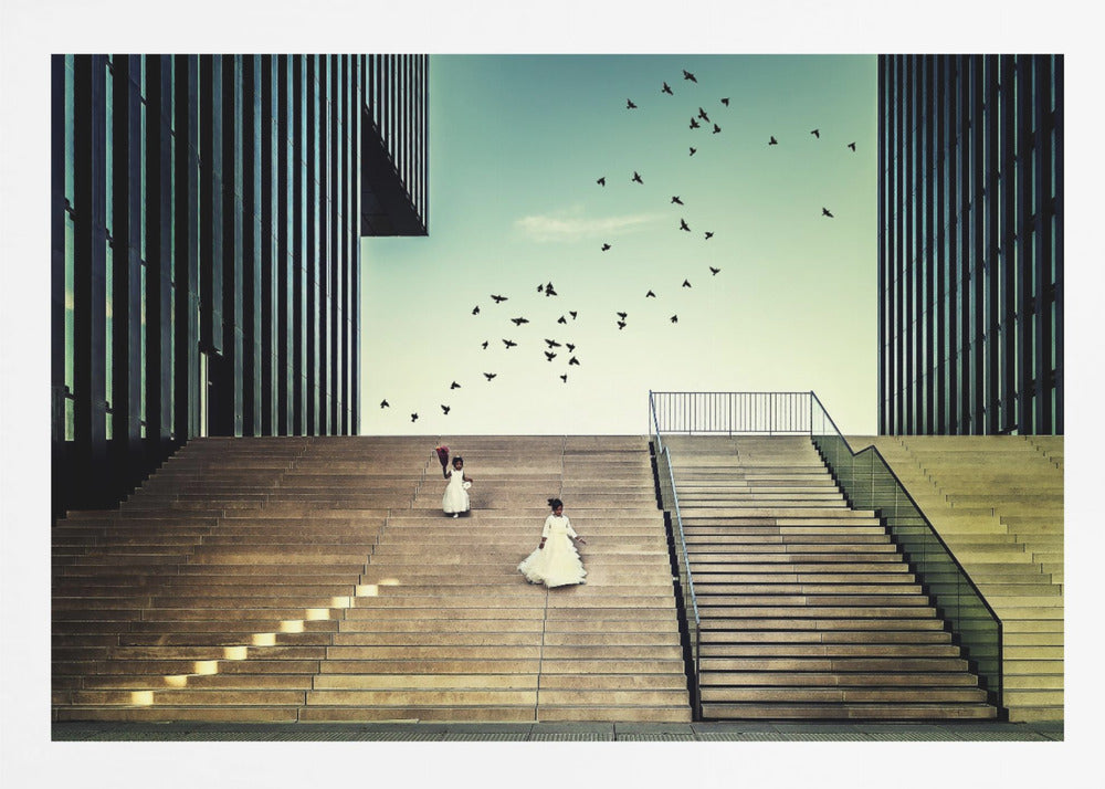 A framed piece of art depicting two young girls in white dresses climbing a vast, modern concrete staircase flanked by two towering, dark buildings. A large flock of birds flies through the teal sky above them, adding a sense of movement to the structured, architectural scene. Poster