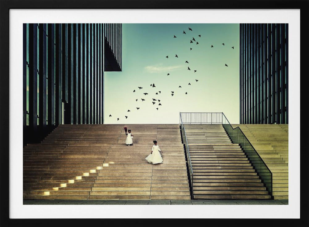 A framed piece of art depicting two young girls in white dresses climbing a vast, modern concrete staircase flanked by two towering, dark buildings. A large flock of birds flies through the teal sky above them, adding a sense of movement to the structured, architectural scene. Poster