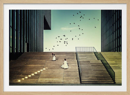 A framed piece of art depicting two young girls in white dresses climbing a vast, modern concrete staircase flanked by two towering, dark buildings. A large flock of birds flies through the teal sky above them, adding a sense of movement to the structured, architectural scene. Poster
