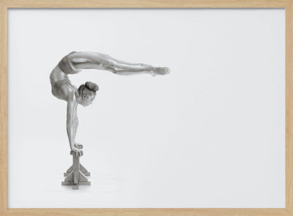 A framed black and white photograph of a female gymnast with a metallic silver-painted body, balancing in a difficult handstand pose on small blocks against a stark white background. Her back is arched and her legs are extended straight out behind her, parallel to the ground. Artwork