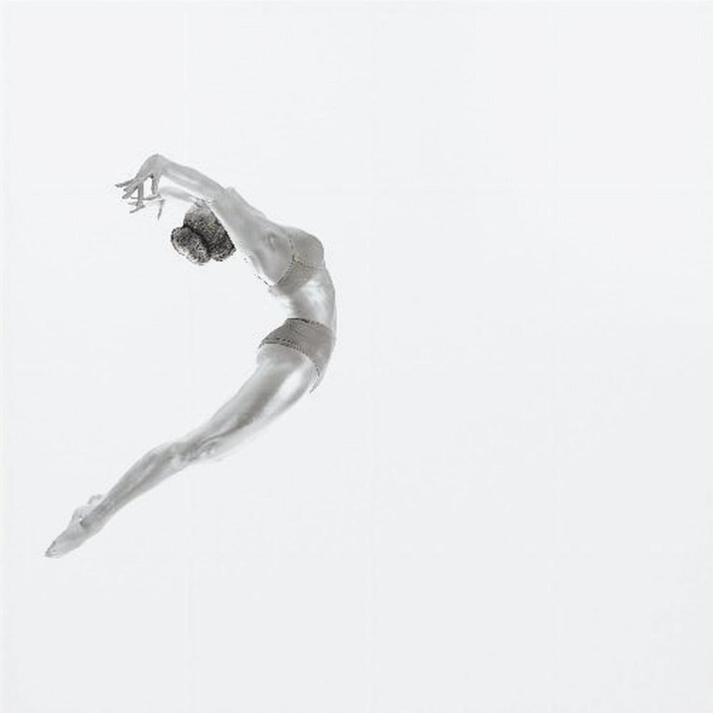 A minimalist black and white photograph of a graceful dancer frozen in mid-air, her body arched backward in an elegant C-shape against a stark white background. The artwork is presented in a light wood frame. Decor