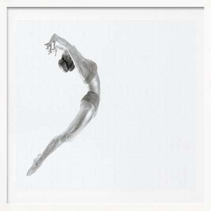 A minimalist black and white photograph of a graceful dancer frozen in mid-air, her body arched backward in an elegant C-shape against a stark white background. The artwork is presented in a light wood frame. Decor