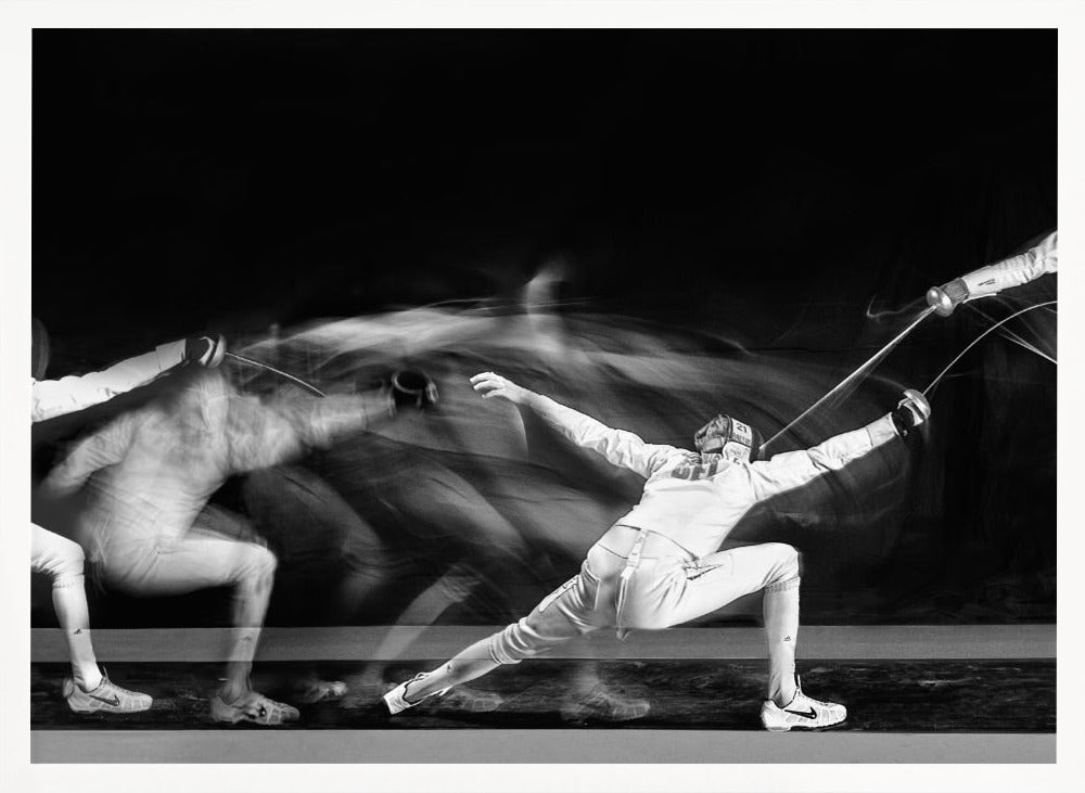 A framed, dramatic black and white photograph using long exposure to capture a fencer in motion. The fencer, in full white gear, lunges forward, their form crisp at the end of the movement while a ghostly blur trails behind, illustrating their rapid advance against a black background. Decor