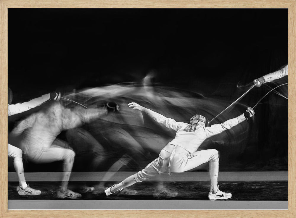 A framed, dramatic black and white photograph using long exposure to capture a fencer in motion. The fencer, in full white gear, lunges forward, their form crisp at the end of the movement while a ghostly blur trails behind, illustrating their rapid advance against a black background. Decor