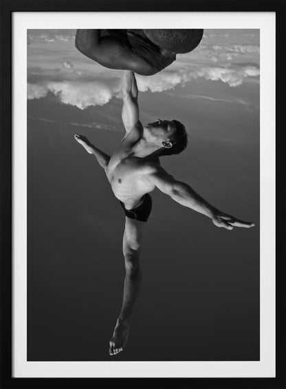 A surreal black and white photograph of two male acrobats. One man, in a graceful dance-like pose balancing on one leg, holds another man aloft with a single outstretched arm. The man being held is upside down against a backdrop of clouds, creating a gravity-defying and artistic illusion. Print