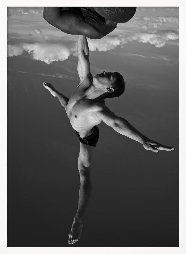 A surreal black and white photograph of two male acrobats. One man, in a graceful dance-like pose balancing on one leg, holds another man aloft with a single outstretched arm. The man being held is upside down against a backdrop of clouds, creating a gravity-defying and artistic illusion. Print