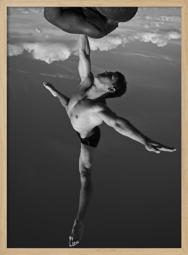 A surreal black and white photograph of two male acrobats. One man, in a graceful dance-like pose balancing on one leg, holds another man aloft with a single outstretched arm. The man being held is upside down against a backdrop of clouds, creating a gravity-defying and artistic illusion. Print