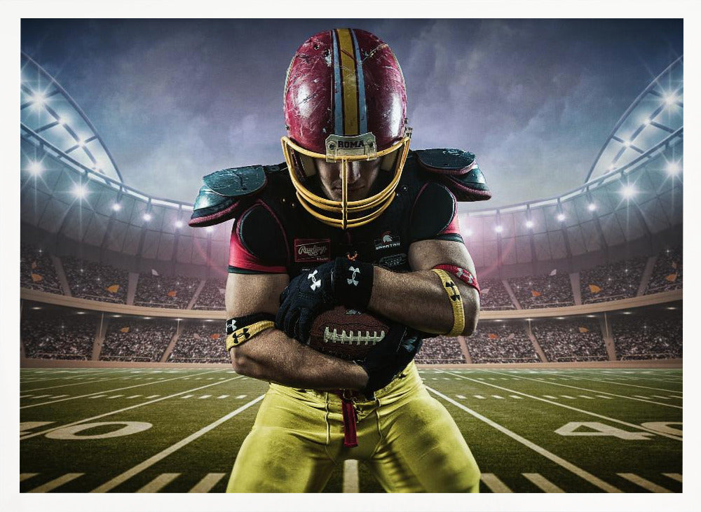 A framed poster of a determined football player in a red and yellow uniform standing on a field in a packed stadium. He is holding a football close to his chest with his head bowed, under bright stadium lights. Decor