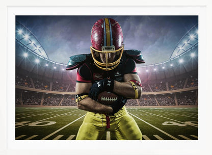 A framed poster of a determined football player in a red and yellow uniform standing on a field in a packed stadium. He is holding a football close to his chest with his head bowed, under bright stadium lights. Decor