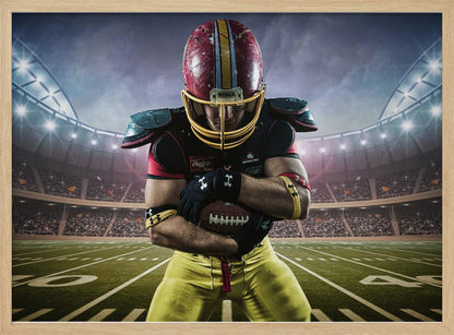 A framed poster of a determined football player in a red and yellow uniform standing on a field in a packed stadium. He is holding a football close to his chest with his head bowed, under bright stadium lights. Decor