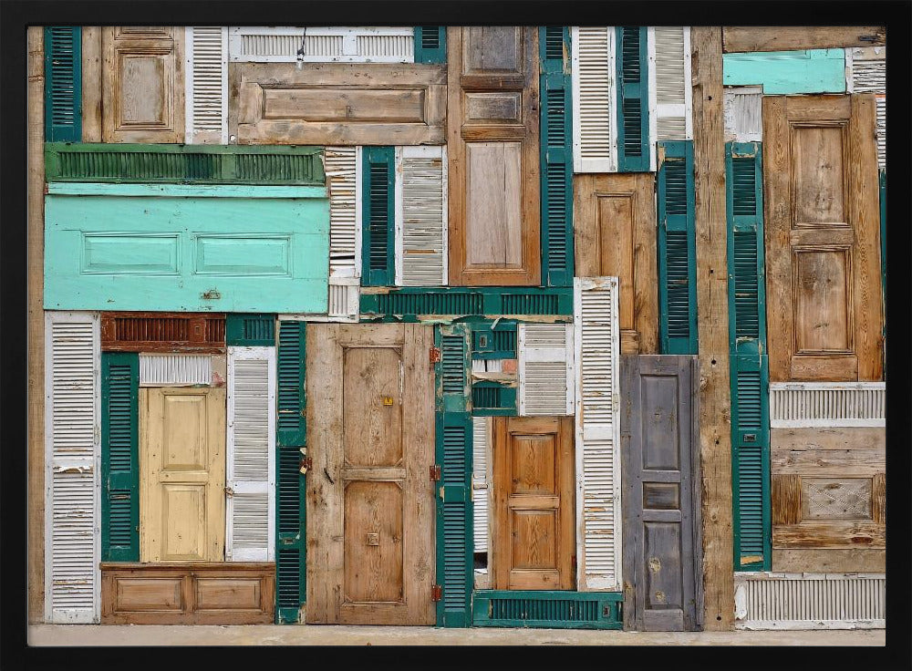 A framed art piece featuring a chaotic collage of various old, weathered wooden doors and window shutters arranged in a dense patchwork, showcasing a rustic texture and colors like natural wood, teal, green, and distressed white. Wall Art