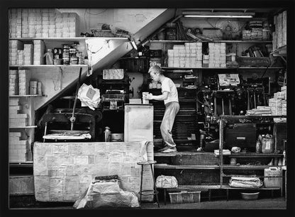 A vintage art print depicting a small, old-fashioned printing shop interior, showcasing antique machinery and a nostalgic atmosphere. Artwork
