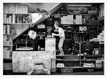A vintage art print depicting a small, old-fashioned printing shop interior, showcasing antique machinery and a nostalgic atmosphere. Artwork