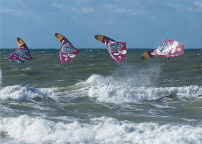 A composite, silver-framed photograph capturing the four stages of a windsurfer's impressive jump over choppy, white-capped ocean waves under a partly cloudy blue sky. Print