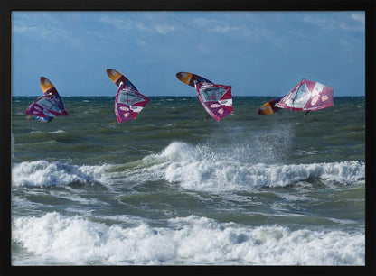 A composite, silver-framed photograph capturing the four stages of a windsurfer's impressive jump over choppy, white-capped ocean waves under a partly cloudy blue sky. Print
