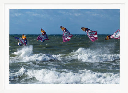 A composite, silver-framed photograph capturing the four stages of a windsurfer's impressive jump over choppy, white-capped ocean waves under a partly cloudy blue sky. Print
