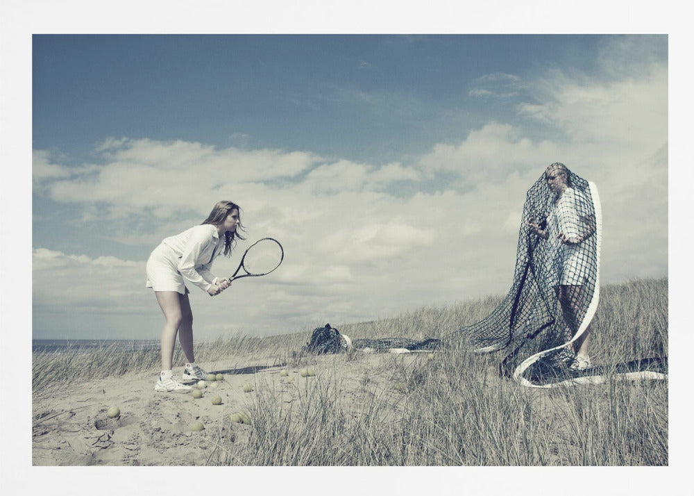 A surreal photograph of two women on a grassy sand dune. One woman is dressed in white tennis attire, bent over and ready to hit a ball with her racket. The other woman stands opposite her, entangled and draped in a large tennis net. The scene is under a cloudy blue sky and has a desaturated, cool-toned color palette, framed in silver. Decor