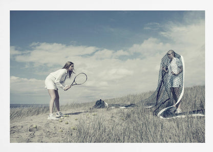 A surreal photograph of two women on a grassy sand dune. One woman is dressed in white tennis attire, bent over and ready to hit a ball with her racket. The other woman stands opposite her, entangled and draped in a large tennis net. The scene is under a cloudy blue sky and has a desaturated, cool-toned color palette, framed in silver. Decor