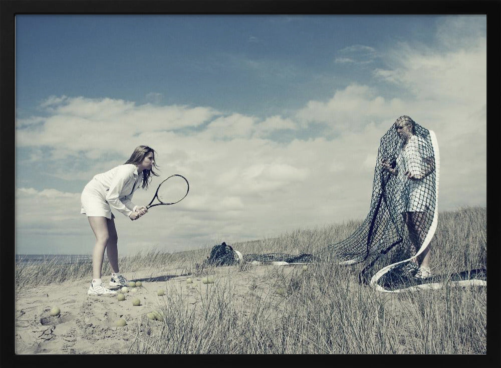 A surreal photograph of two women on a grassy sand dune. One woman is dressed in white tennis attire, bent over and ready to hit a ball with her racket. The other woman stands opposite her, entangled and draped in a large tennis net. The scene is under a cloudy blue sky and has a desaturated, cool-toned color palette, framed in silver. Decor