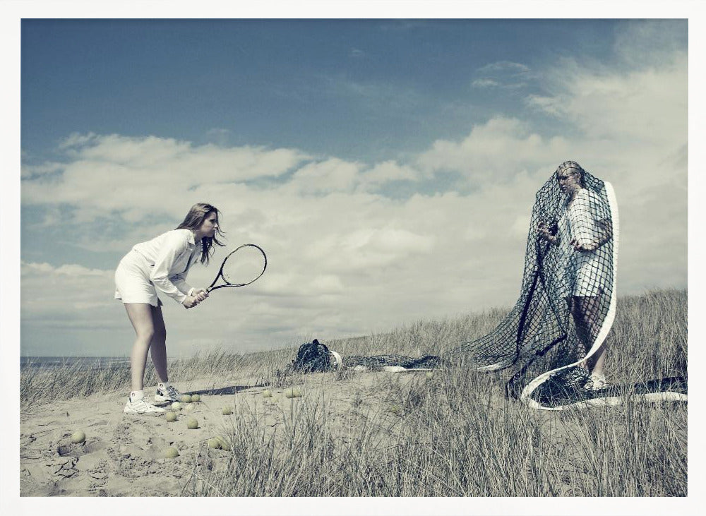 A surreal photograph of two women on a grassy sand dune. One woman is dressed in white tennis attire, bent over and ready to hit a ball with her racket. The other woman stands opposite her, entangled and draped in a large tennis net. The scene is under a cloudy blue sky and has a desaturated, cool-toned color palette, framed in silver. Decor