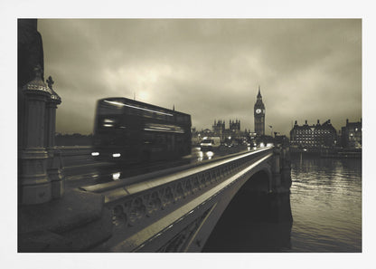A framed, sepia-toned long-exposure photograph of London. A double-decker bus is shown in motion blur as it crosses Westminster Bridge. In the background, the Big Ben clock tower and the Houses of Parliament are visible against a cloudy sky, with lights reflecting on the wet road and the River Thames. Wall Art