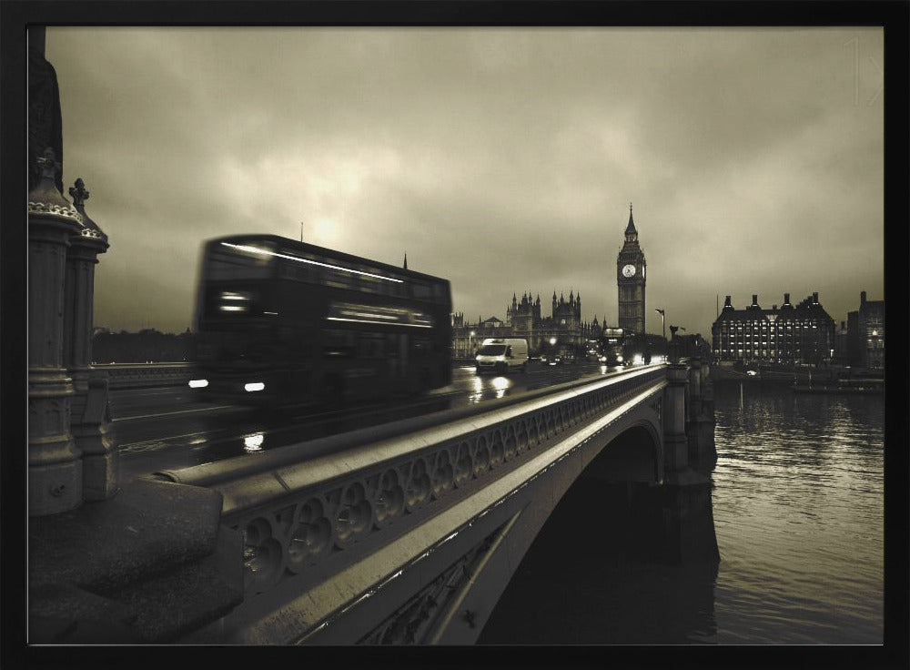 A framed, sepia-toned long-exposure photograph of London. A double-decker bus is shown in motion blur as it crosses Westminster Bridge. In the background, the Big Ben clock tower and the Houses of Parliament are visible against a cloudy sky, with lights reflecting on the wet road and the River Thames. Wall Art