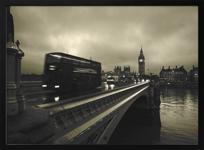 A framed, sepia-toned long-exposure photograph of London. A double-decker bus is shown in motion blur as it crosses Westminster Bridge. In the background, the Big Ben clock tower and the Houses of Parliament are visible against a cloudy sky, with lights reflecting on the wet road and the River Thames. Wall Art