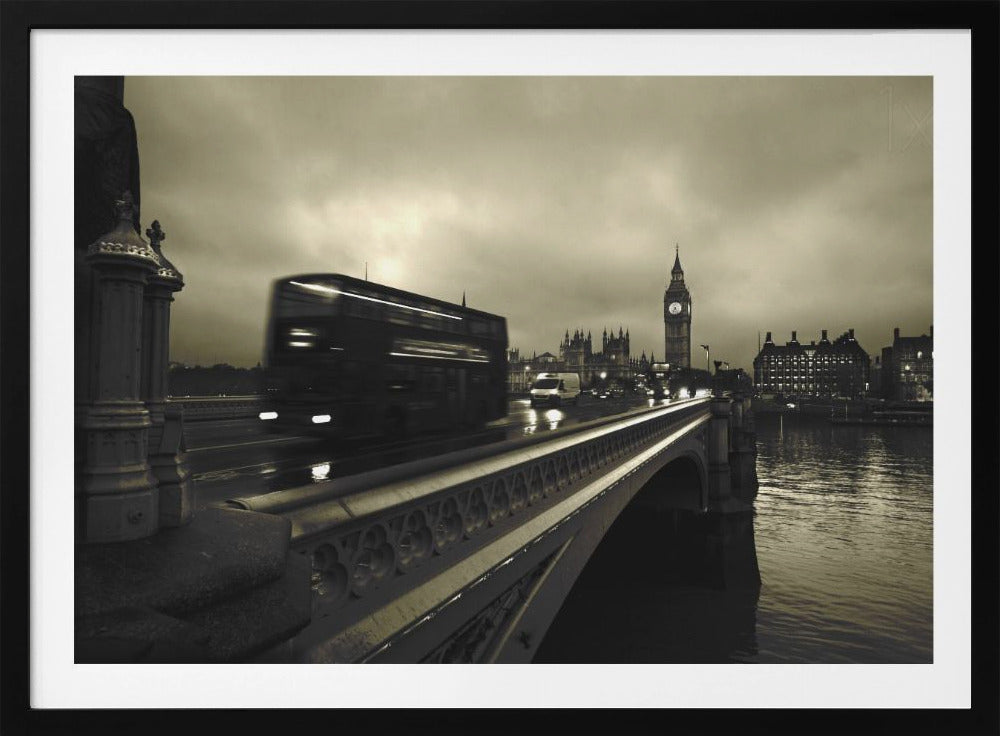 A framed, sepia-toned long-exposure photograph of London. A double-decker bus is shown in motion blur as it crosses Westminster Bridge. In the background, the Big Ben clock tower and the Houses of Parliament are visible against a cloudy sky, with lights reflecting on the wet road and the River Thames. Wall Art