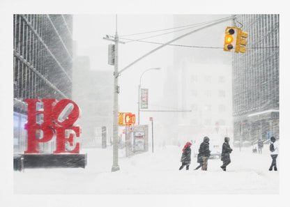 A photograph of a busy city street during a heavy snowstorm. In the foreground on the left, a large, bright red sculpture spells out the word 'HOPE', providing a stark contrast to the muted, white, and gray tones of the snowy scene. Pedestrians in winter coats are crossing the snow-covered street, and tall buildings are partially obscured by the falling snow in the background. Wall Art