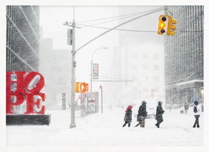 A photograph of a busy city street during a heavy snowstorm. In the foreground on the left, a large, bright red sculpture spells out the word 'HOPE', providing a stark contrast to the muted, white, and gray tones of the snowy scene. Pedestrians in winter coats are crossing the snow-covered street, and tall buildings are partially obscured by the falling snow in the background. Wall Art