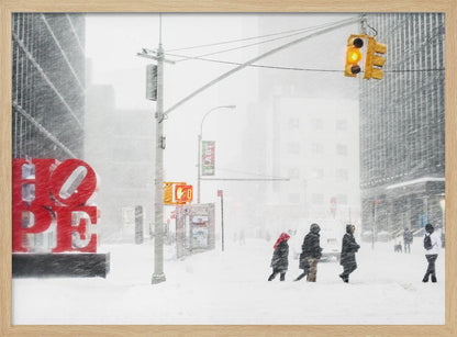 A photograph of a busy city street during a heavy snowstorm. In the foreground on the left, a large, bright red sculpture spells out the word 'HOPE', providing a stark contrast to the muted, white, and gray tones of the snowy scene. Pedestrians in winter coats are crossing the snow-covered street, and tall buildings are partially obscured by the falling snow in the background. Wall Art